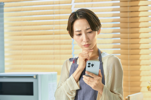 定額減税　スマホをみて悩む女性